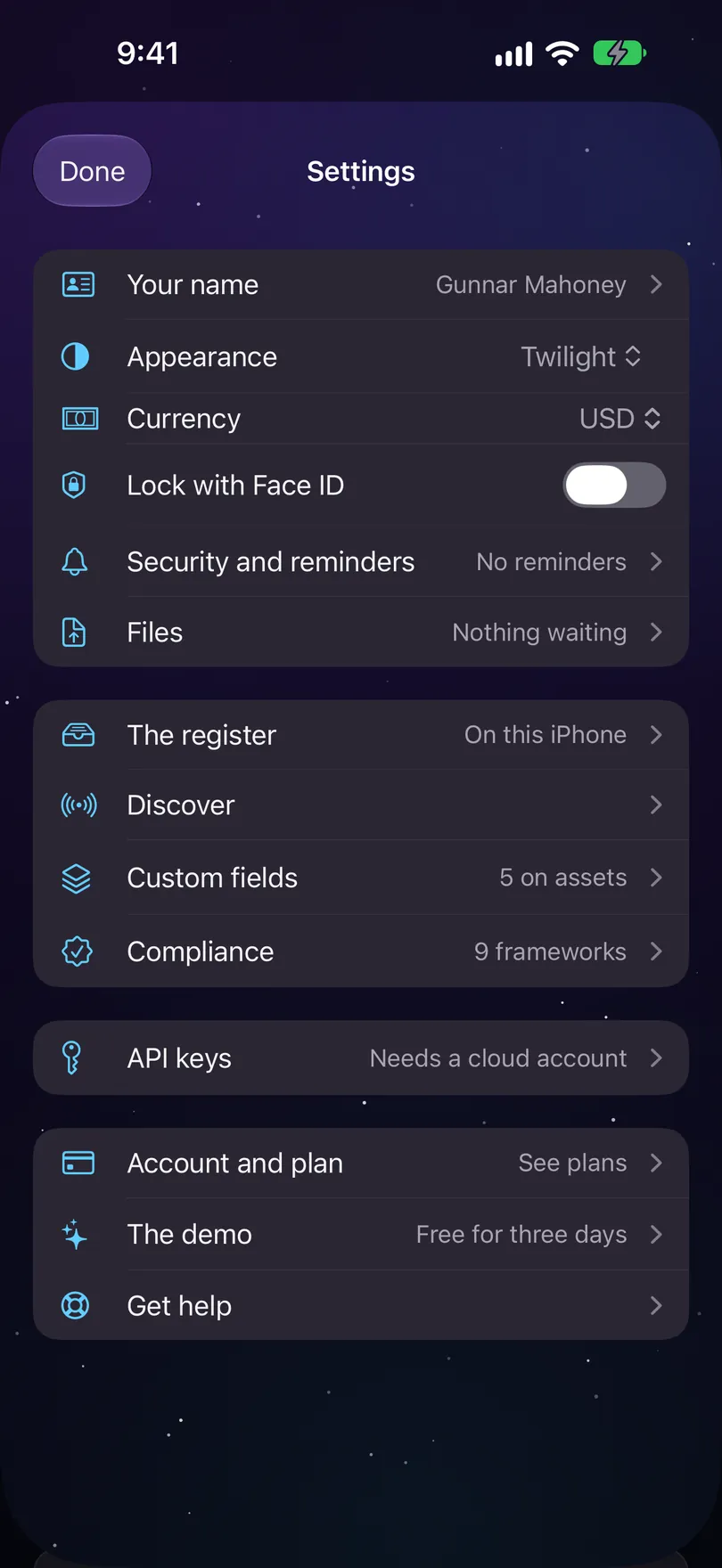 Settings on iPhone, opened over Home with Done: Your name, Appearance Twilight, Currency USD, Lock with Face ID, Security and reminders, Files Nothing waiting; The register On this iPhone, Discover, Custom fields 5 on assets, Compliance 9 frameworks; API keys Needs a cloud account; Account and plan See plans, The demo, Get help.